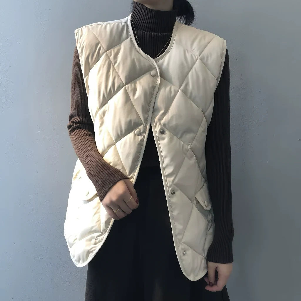 Doudoune sans manche classe blanc cassé portée sur un col roulé marron, fermeture par pressions
