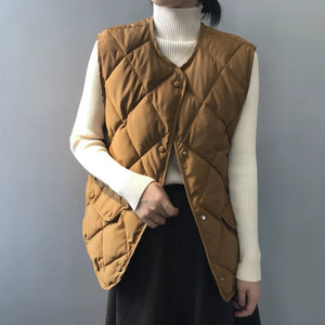 Doudoune sans manche classe camel portée sur un pull crème à col roulé, matelassage en losanges
