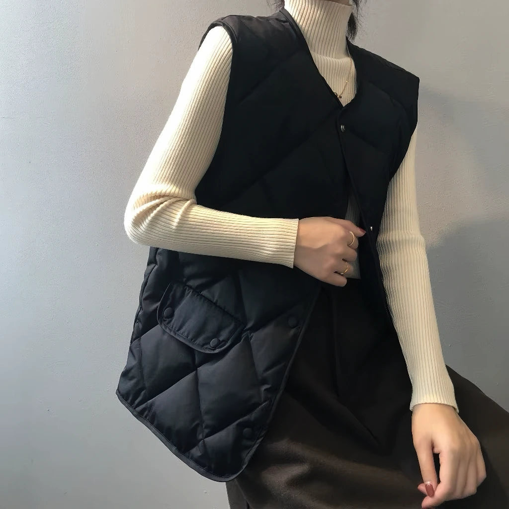Doudoune sans manche classe noire portée ouverte sur un pull crème à col roulé
