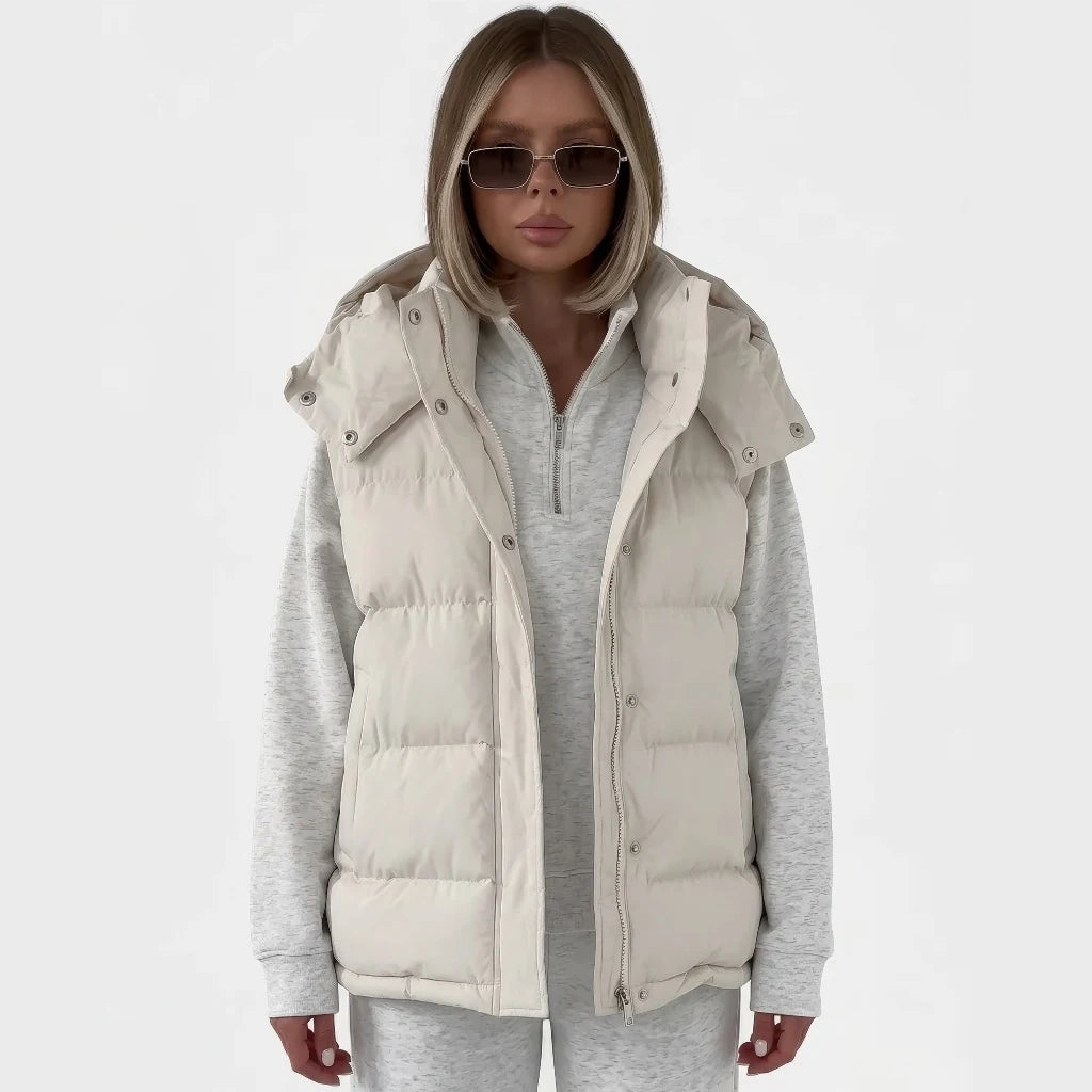 Doudoune sans manche élégante beige portée ouverte sur un sweat gris chiné, capuche amovible