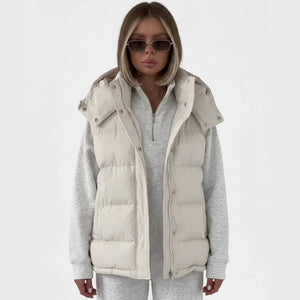 Doudoune sans manche élégante beige portée ouverte sur un sweat gris chiné, capuche amovible