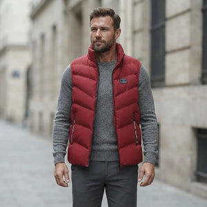 Homme portant la Doudoune sans Manche Matelassée rouge, maille col rond grise et pantalon anthracite