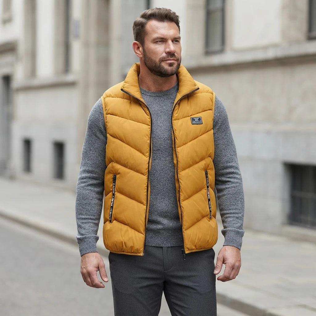 Homme portant la Doudoune sans Manche Moutarde Homme jaune, maille col rond grise et pantalon anthracite