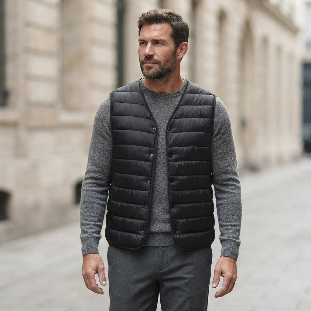 Homme portant la Doudoune Ultra Légère sans Manche noire, maille col rond grise et pantalon anthracite