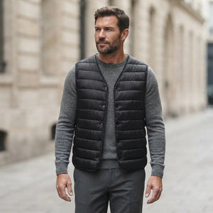 Homme portant la Doudoune Ultra Légère sans Manche noire, maille col rond grise et pantalon anthracite